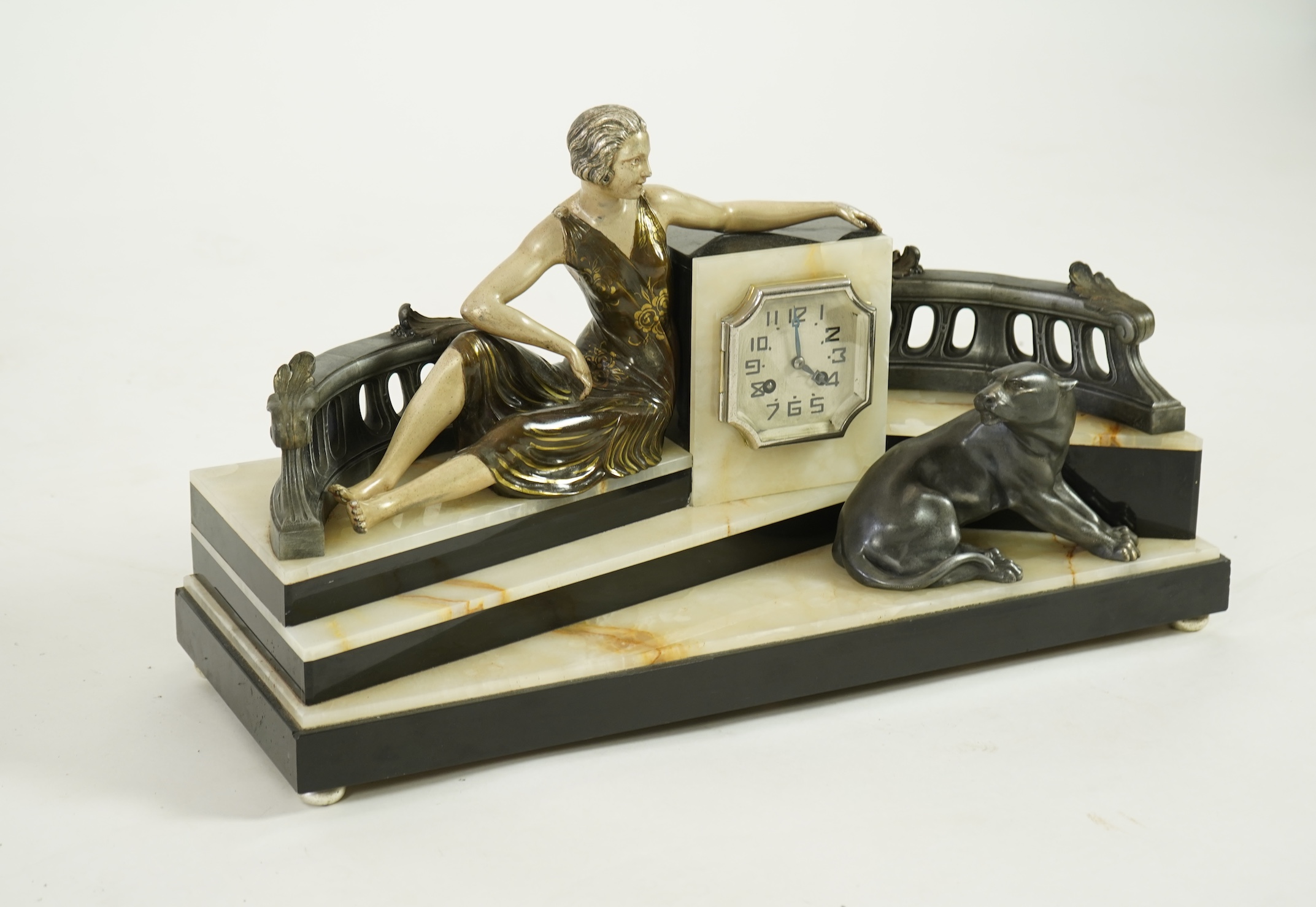 A French Art Deco onyx and patinated spelter clock surmounted with a lady and a black panther on a staircase